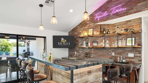 Una zona de bar con un letrero de neón, un logotipo en la pared y una pared de ladrillo con estantes.
