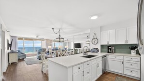 A spacious kitchen with white cabinetry, a large island, and a view to the outside.