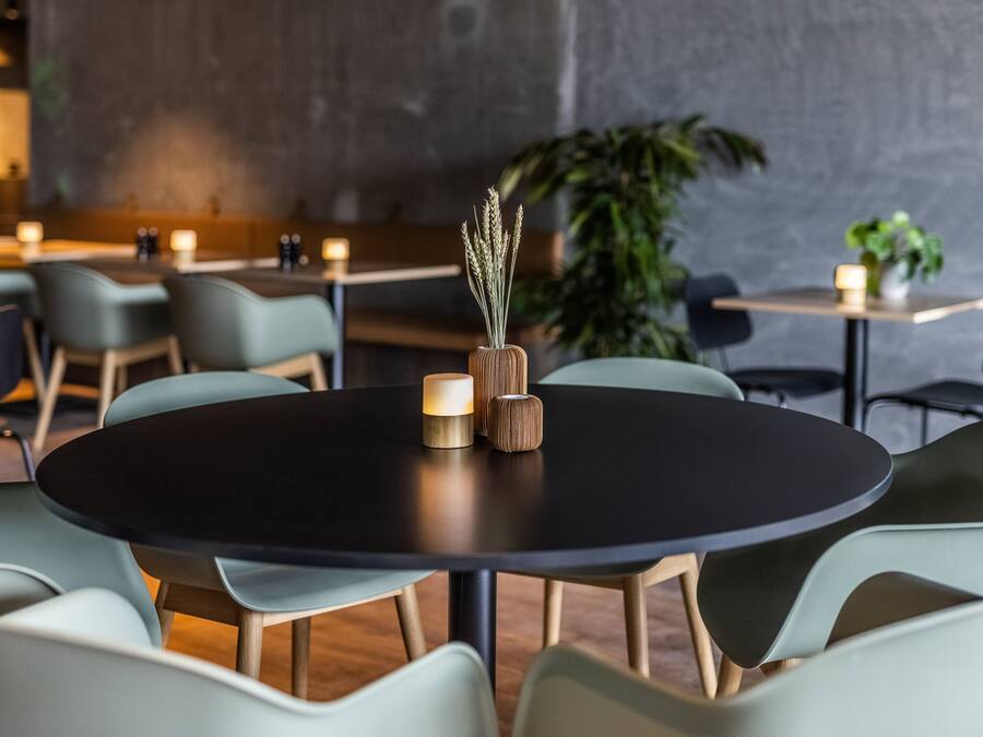 A modern dining area with round tables, light green chairs, and candles.