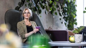 A person seated in a modern office chair with a laptop, surrounded by indoor plants and a small table with a candle and decorative items. - Peak 12 Design Hotel (Viborg)