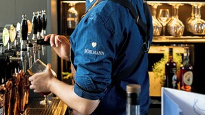 A bartender at a bar with a variety of liquor bottles in the background. - Peak 12 Design Hotel (Viborg)