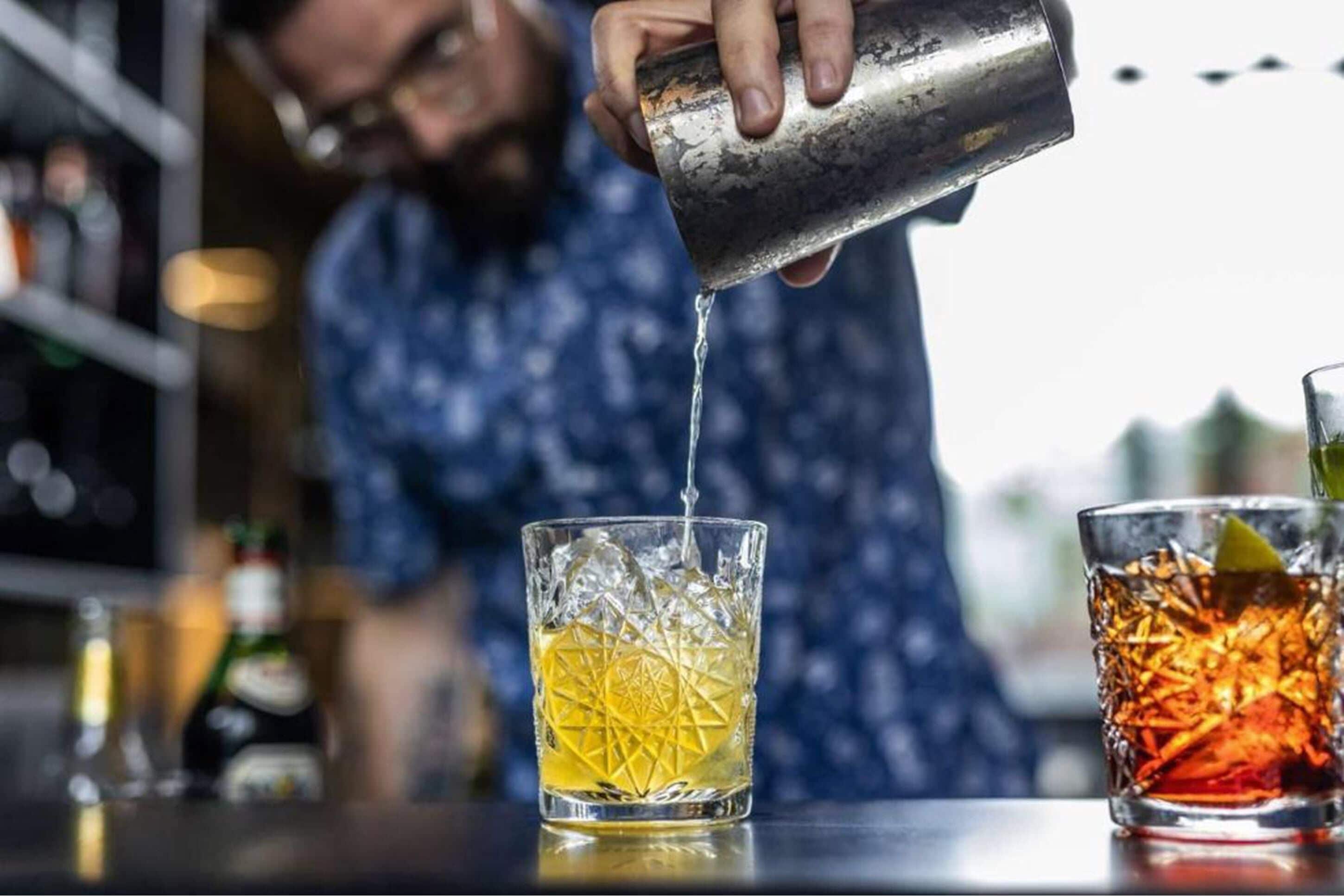 A bartender pouring a drink into a glass.