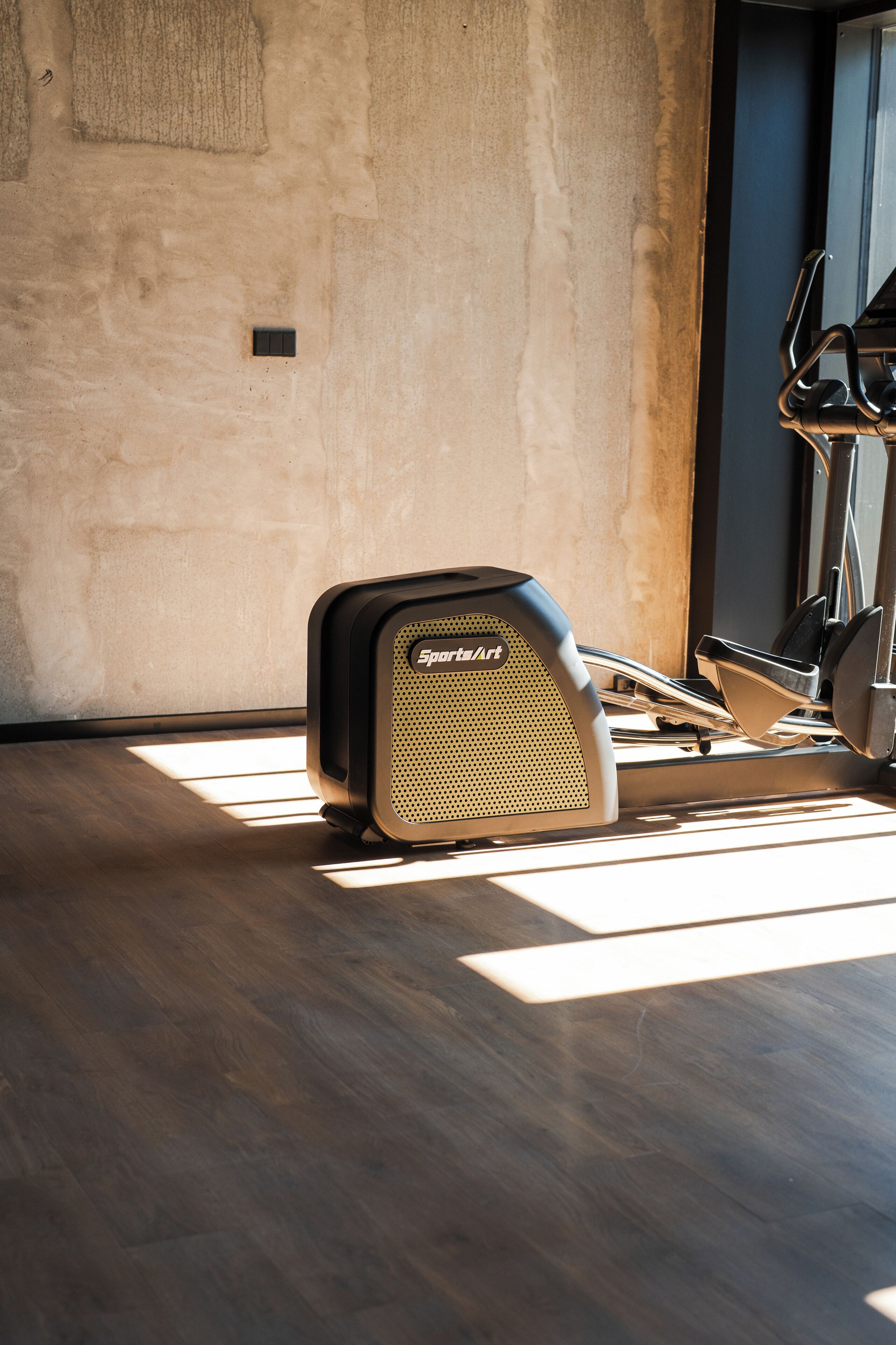 A stationary bike in a room with a wooden floor and a plain wall.