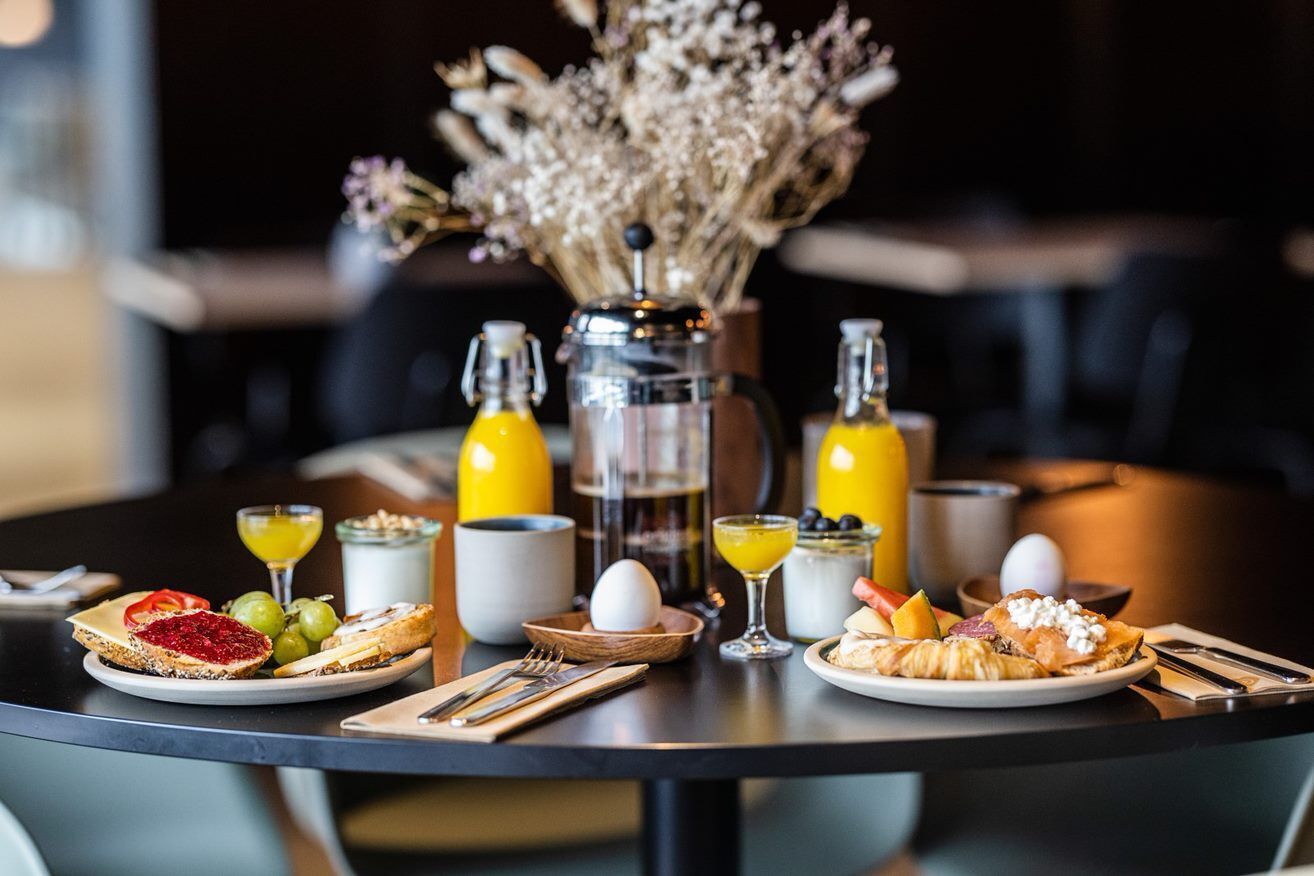 A breakfast setting with plates of food, a coffee pot, and two bottles of orange juice.