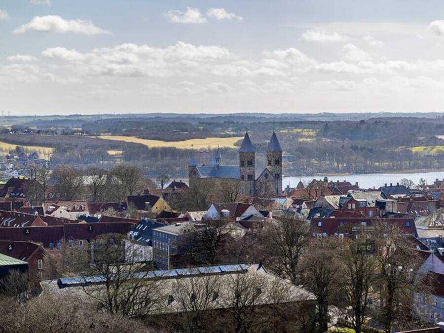 A town with historic buildings, including a church with two towers, and a river in the background.