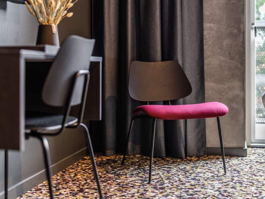 Una habitación moderna con una pared oscura, un escritorio, una silla y una ventana con cortinas.