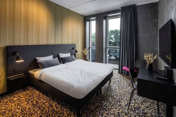 A modern hotel room with a large bed, a desk, and a TV. - Peak 12 Design Hotel (Viborg)