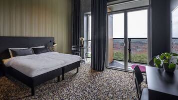 Une chambre d’hôtel moderne avec un grand lit, une petite table agrémentée d’une plante et un balcon offrant une vue agréable.