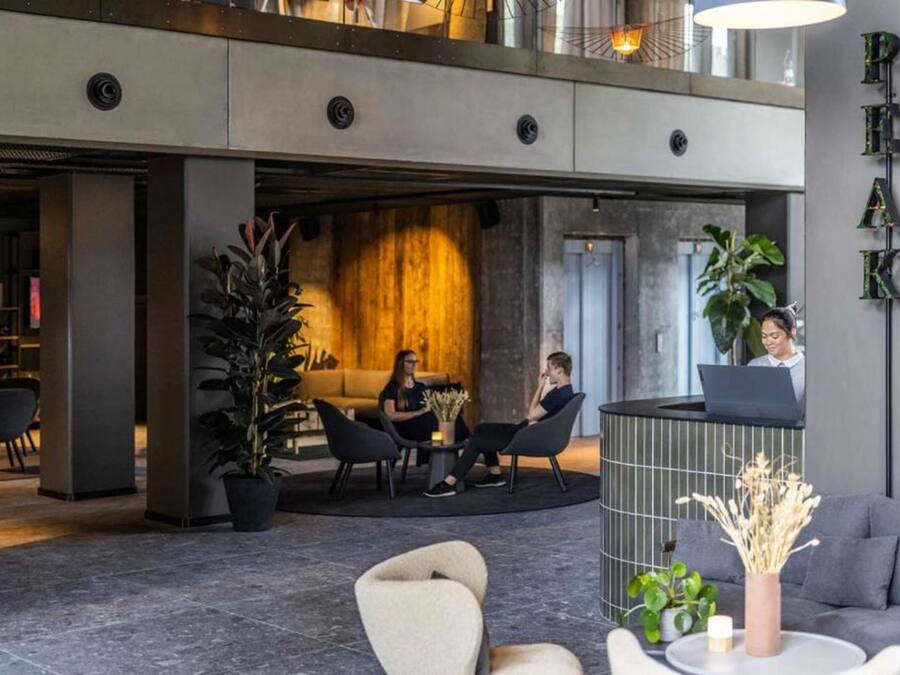 A modern lobby with a reception desk, seating area, and a large plant.