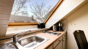 A kitchen with a window, stainless steel sink, and a coffee maker. - Haus Frier (Helgoland)