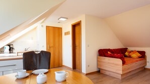 A compact living space with a kitchenette, a dining area, and a sofa bed. - Haus Frier (Helgoland)