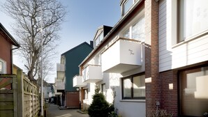 A row of townhouses with attached balconies, a brick facade, and a clear sky. - Haus Frier (Helgoland)