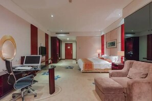 Habitación de hotel con escritorio, silla, cama y un espejo grande.