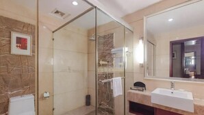 A modern bathroom with a glass-enclosed shower, a white sink, and a marble-tiled wall. - Dynasty Commercial Hotel (Zhongshan)