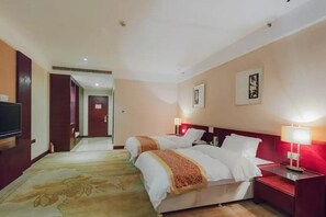 Habitación de hotel con dos camas, televisión, mesita de noche roja y piso alfombrado.