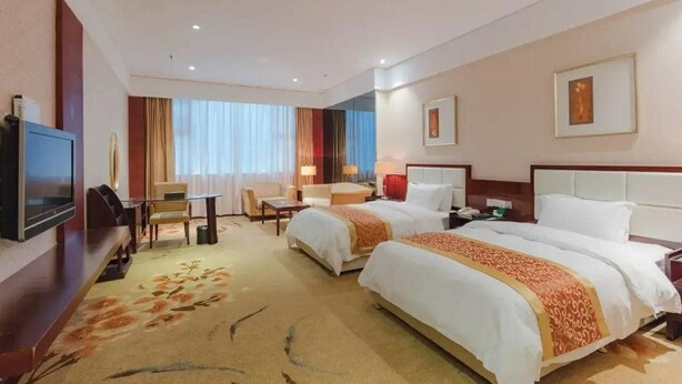 A hotel room with two beds, a TV, a desk, and a chair. - Dynasty Commercial Hotel (Zhongshan)