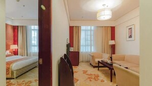 A hotel room with a bed, a sofa, a desk, and a chair. - Dynasty Commercial Hotel (Zhongshan)