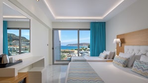 A modern hotel room with a large bed, a desk, and a view of the sea. - Oceanis Park Hotel (Rhodes)