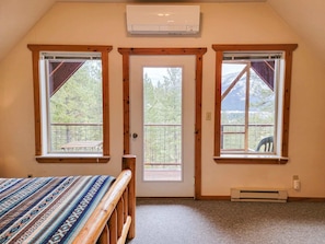 A room with a bed, a door, and two windows with wooden frames.
