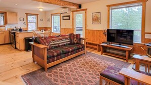 Een gezellig cabin interieur met een eethoek, keuken en een groot raam met uitzicht op de natuur.