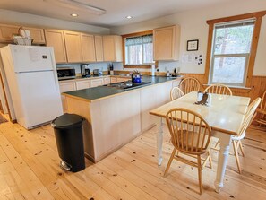 A compact kitchen with wooden cabinets, a refrigerator, a microwave, and a sink.