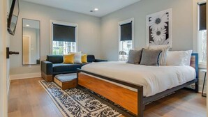 A bedroom with a bed, a sofa, a coffee table, and a large window. - Spacious 4BR, Rooftop Patio, Garage, Walk to Faves |  5 Mins to Nissan Stadium, Less than 10 Mins to Broadway, 24 Hr Hospitality, Great for Groups (Nashville)