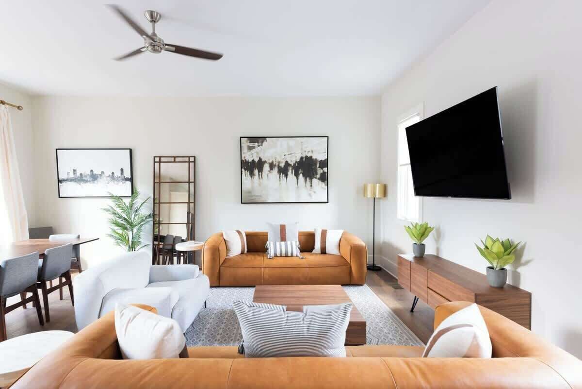 Ein modernes Wohnzimmer mit einem braunen Sofa, einem Couchtisch und einem an der Wand befestigten Fernseher.
