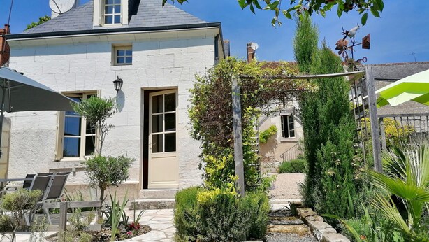 A house with a stone facade, a garden with various plants, a wooden pergola, and a pathway leading to the entrance. - 2 Gites 8 Personnes Proche Beauval et Chenonceaux (Montrichard Val de Cher)