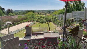 A garden with a red umbrella, wicker furniture, and a view of the countryside. - 2 Gites 8 Personnes Proche Beauval et Chenonceaux (Montrichard Val de Cher)