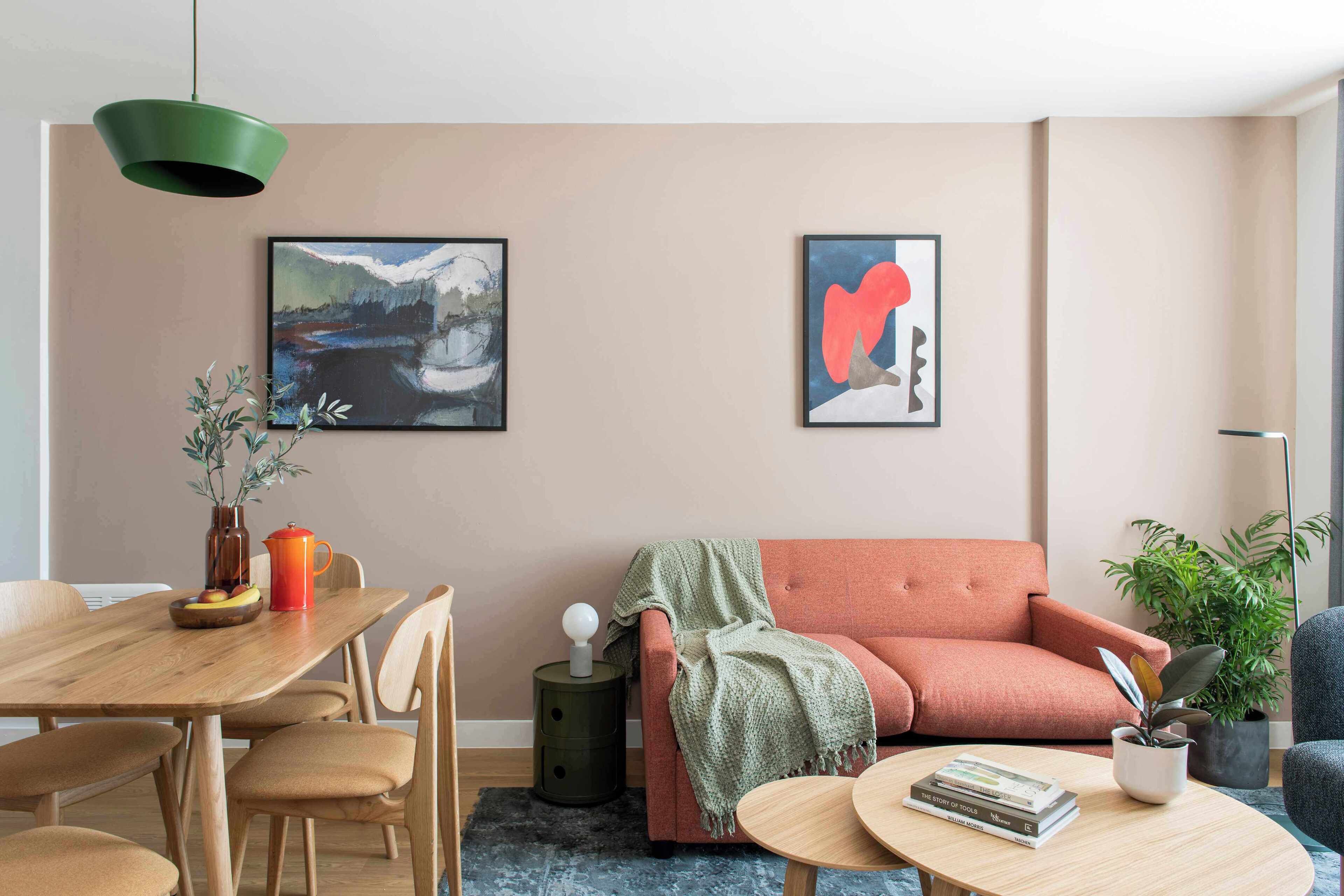 Ein modernes Wohnzimmer mit einem Holzespeisetisch, einer Couch und zwei gerahmten abstrakten Bildern an der Wand.