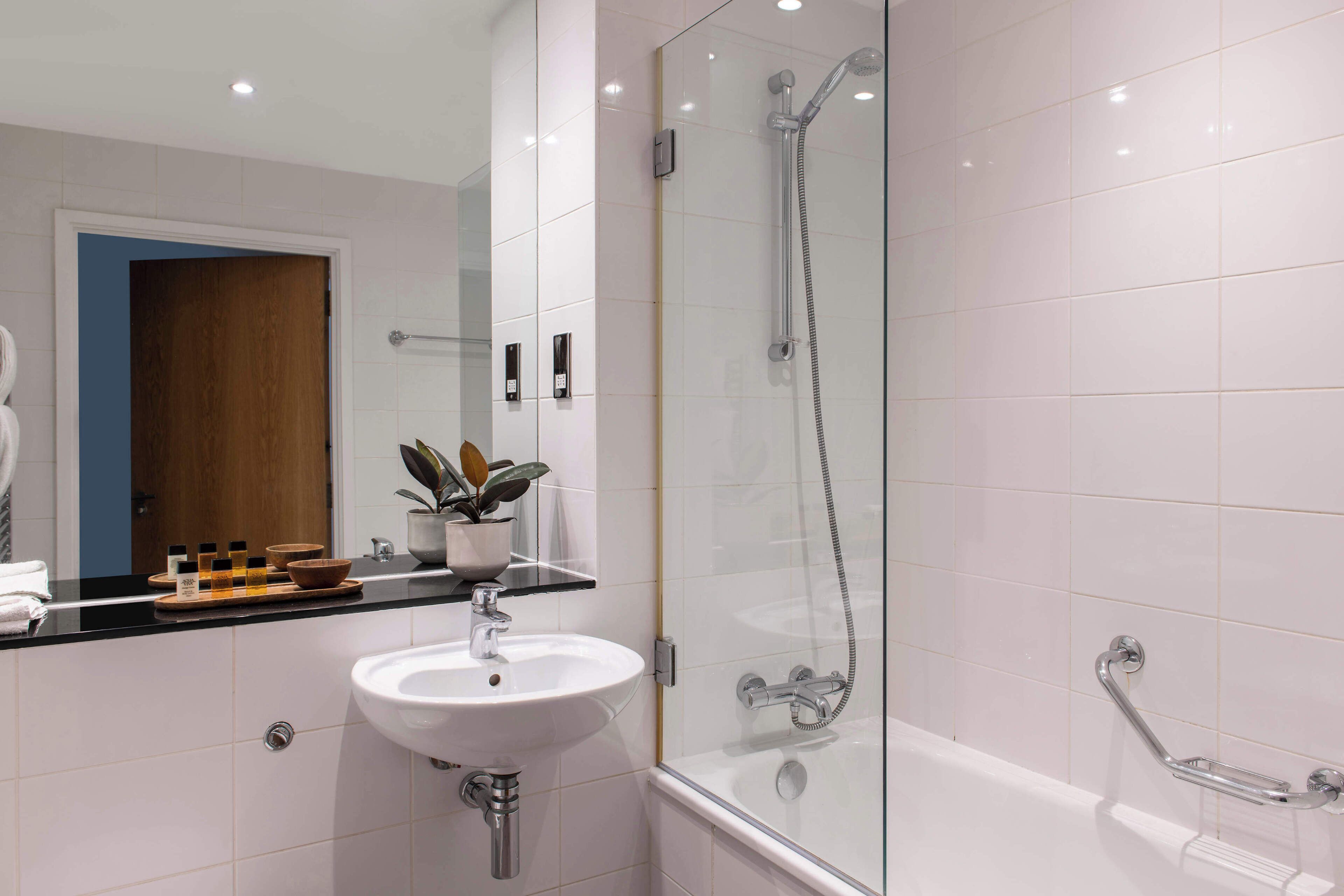 Un baño moderno con cabina de ducha de vidrio, un lavabo blanco y una bañera.