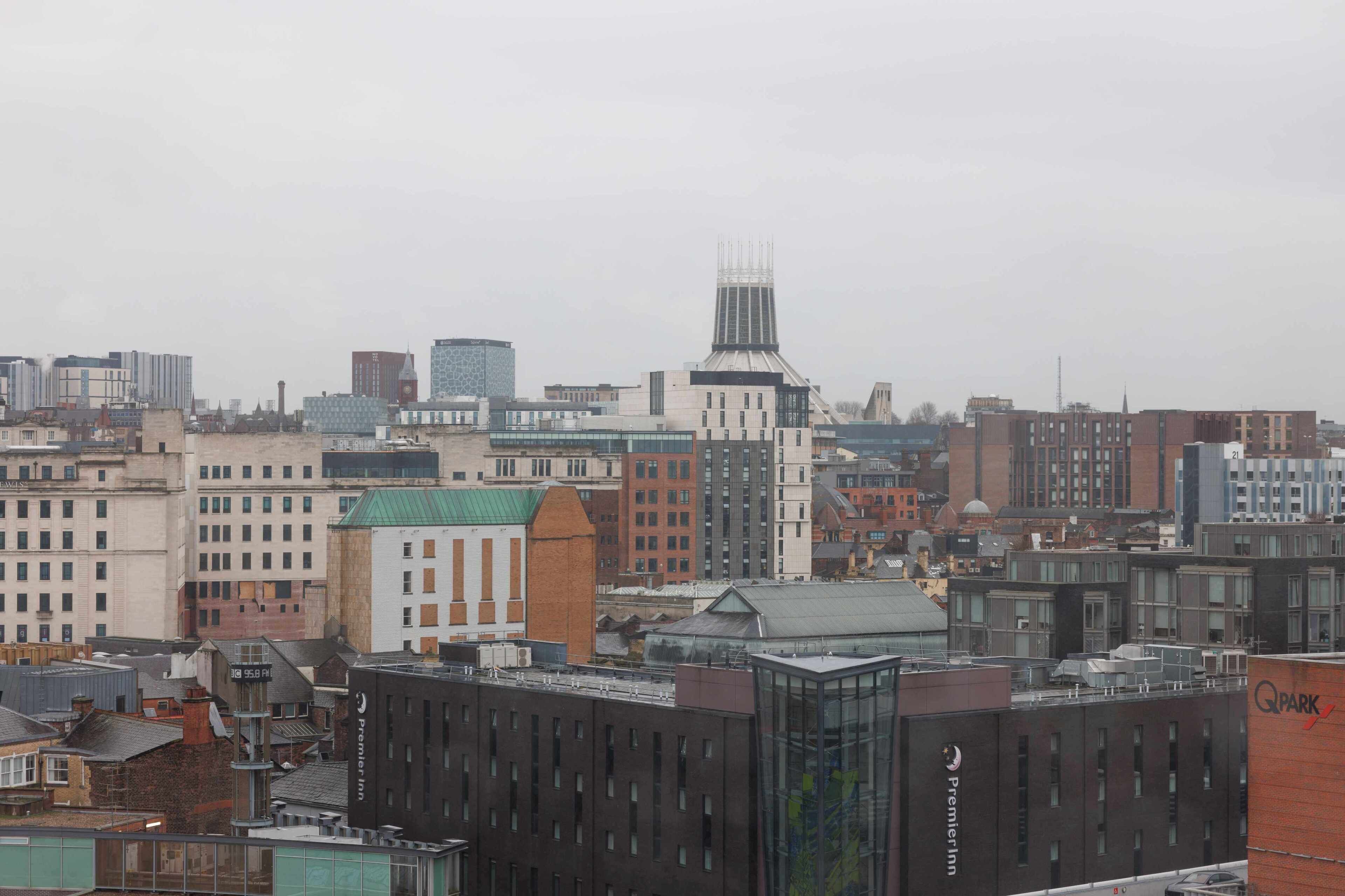 A cityscape with various buildings, including a prominent hotel with a distinctive tower and a modern building with a glass facade.