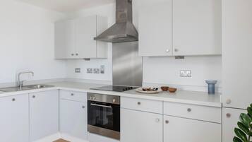 Una cocina moderna con armarios blancos, electrodomésticos de acero inoxidable y horno empotrado.