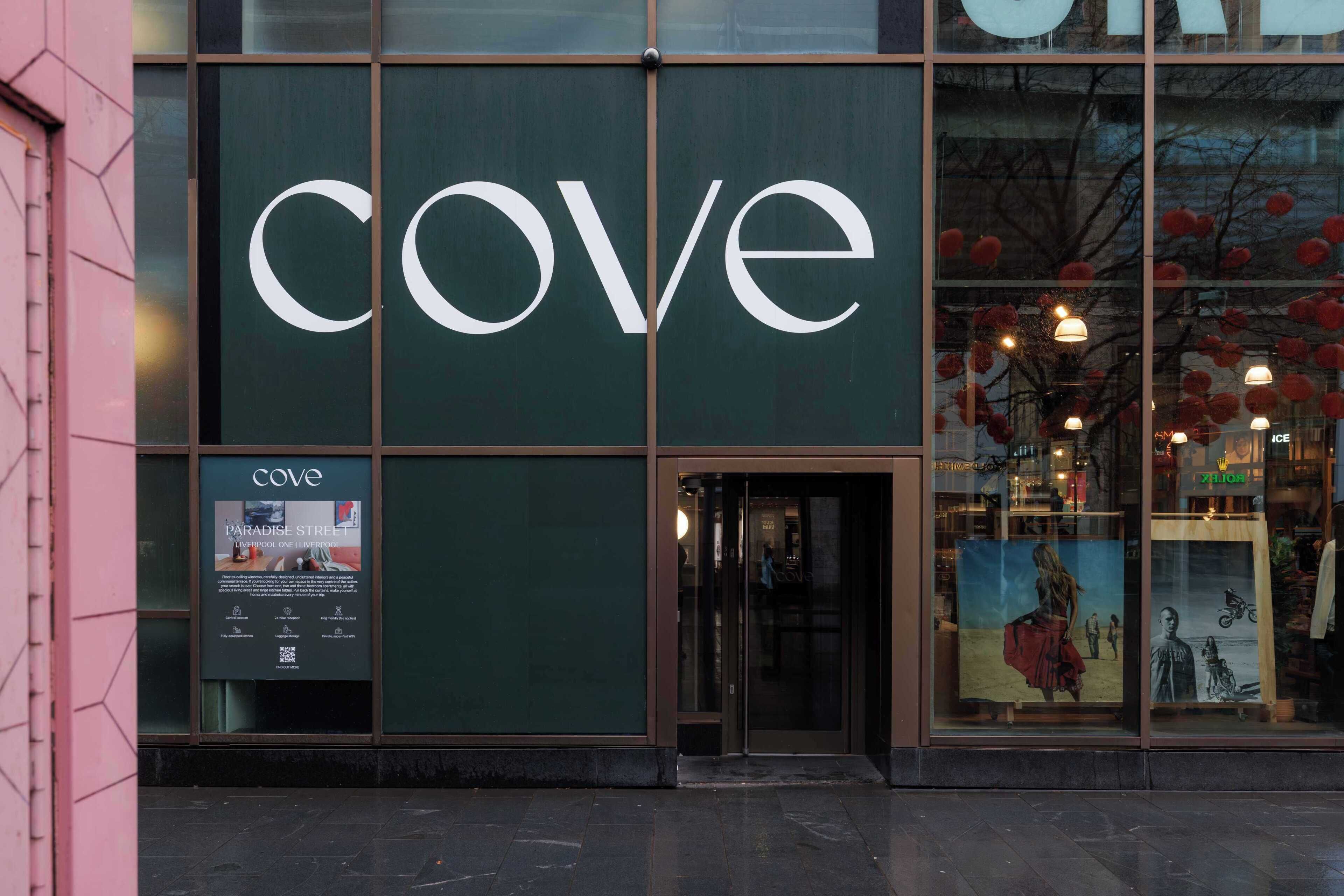 A storefront with a large 'cove' sign, a glass door entrance, and a poster advertising 'Paradise Street.'