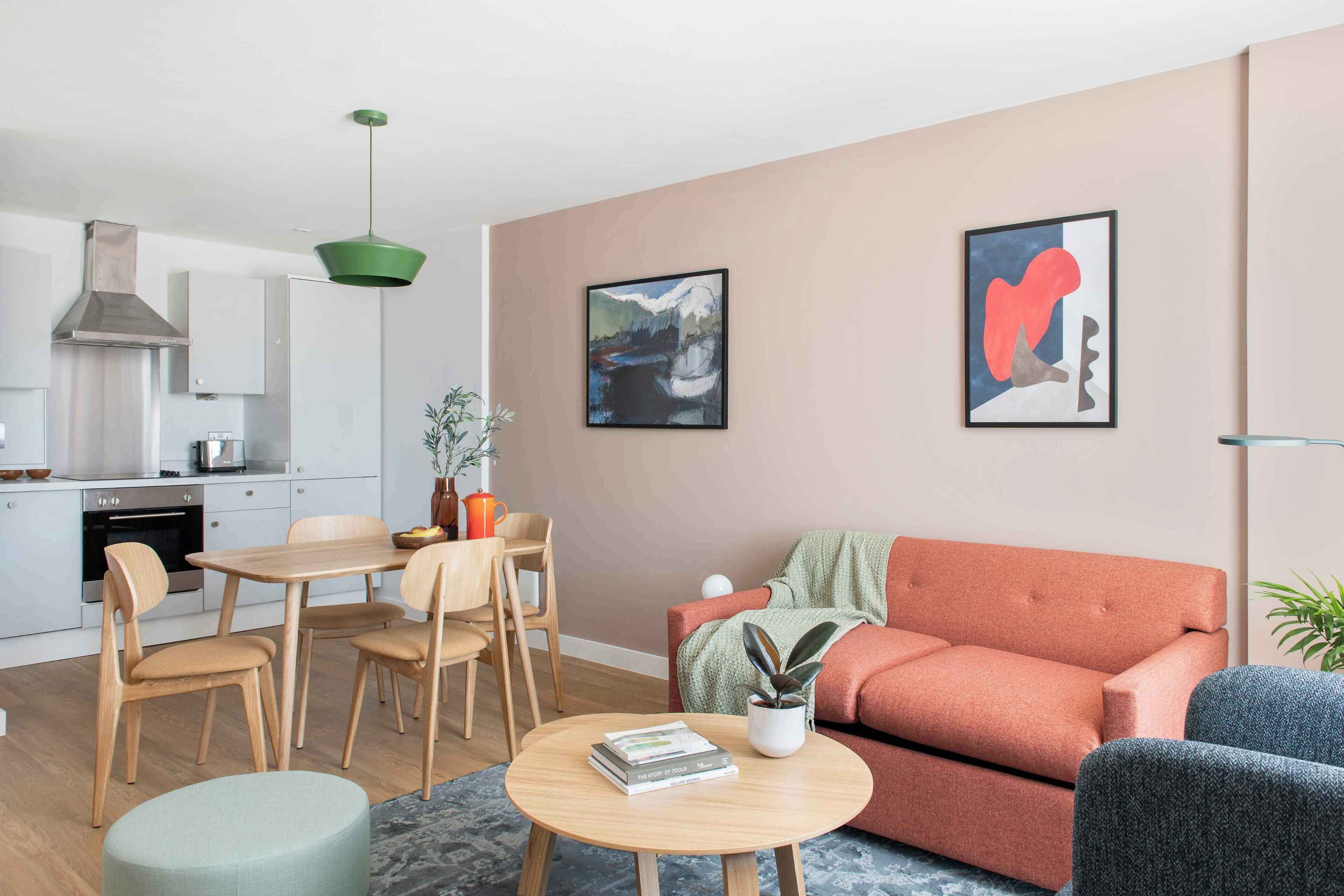 A modern living room with a sofa, a dining table with chairs, a coffee table, and a kitchen area in the background.