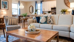 Una sala de estar moderna con una mesa de centro de madera, un sofá con cojines estampados y un comedor con una mesa y sillas de madera.