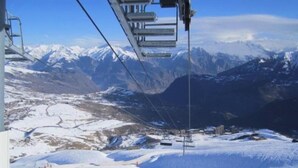 Eine Seilbahn über eine verschneite Landschaft mit Bergen im Hintergrund.