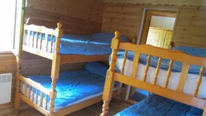 Eine Holzhütte mit drei Etagenbetten, Holzwänden und einem kleinen Fenster.