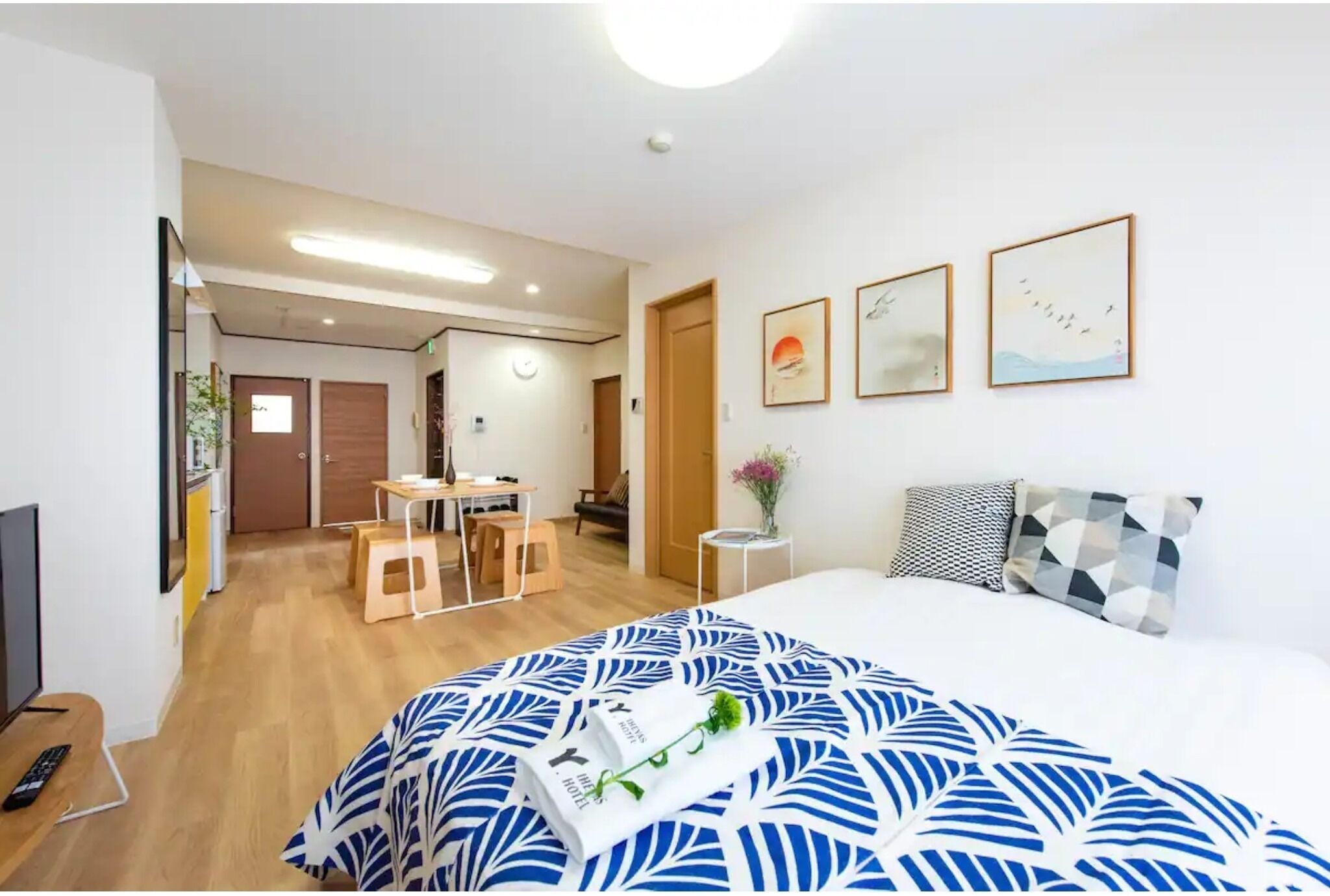 A hotel room with a bed, a desk, a chair, a small table, and a TV.