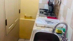 Een kleine keuken met een spoelbak, een fornuis en een kast.