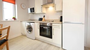 A compact kitchen with a washing machine, oven, microwave, and a refrigerator. - 1 bed Apartment Close to Football Grounds (Liverpool)