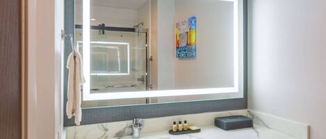 A bathroom with a large mirror, a sink, and a towel rack.