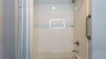 A modern bathroom with a walk-in shower, a bathtub, and a handrail.