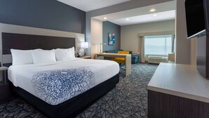 Une chambre d’hôtel avec un grand lit, un bureau, une chaise, une télévision et une fenêtre donnant sur un beau paysage.