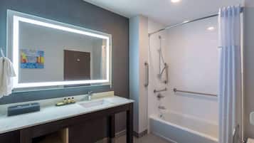 A modern bathroom with a large mirror, a bathtub, and a shower.
