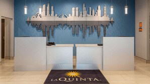 Un comptoir d’accueil avec un mur bleu et une décoration représentant un paysage urbain au-dessus.