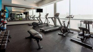Une salle de sport moderne équipée de tapis de course, de vélos d’appartement et d’appareils de musculation.