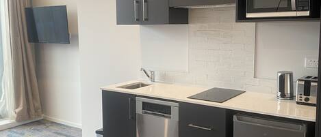 A modern kitchen with grey cabinets, a built-in microwave, a dishwasher, and a sink.