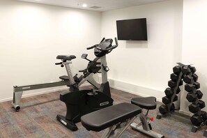 A gym with a treadmill, bench, and dumbbells.