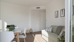 A modern living room with a sofa, chairs, a dining table, and a potted plant.